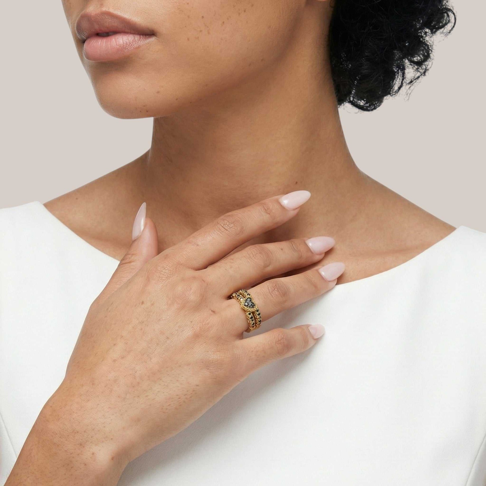 Close-up of a person wearing a gold ring with a gemstone on a plain background