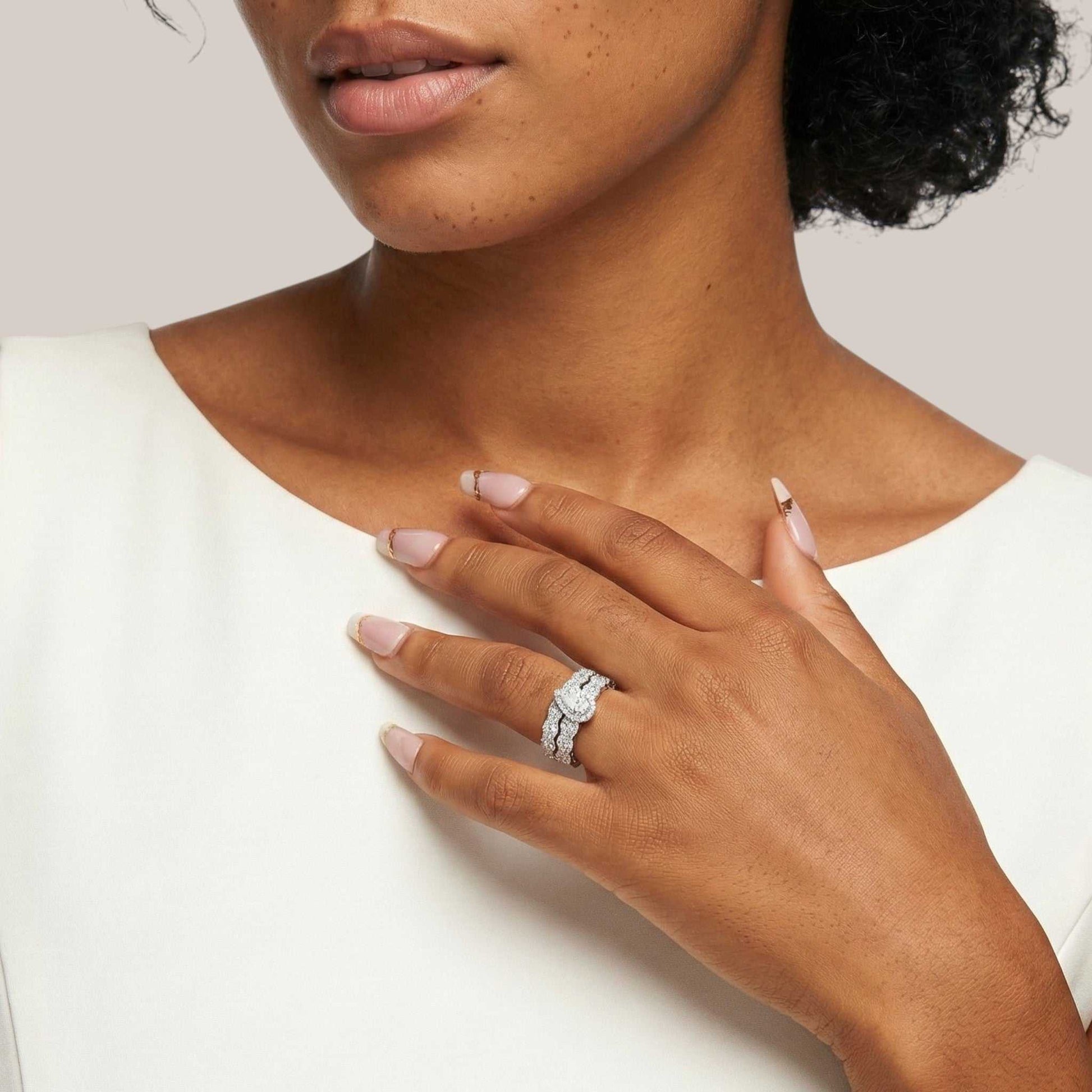 Close-up of a woman's hand wearing a diamond ring on a plain background
