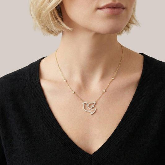 Necklace with a dove pendant worn by a person against a neutral background