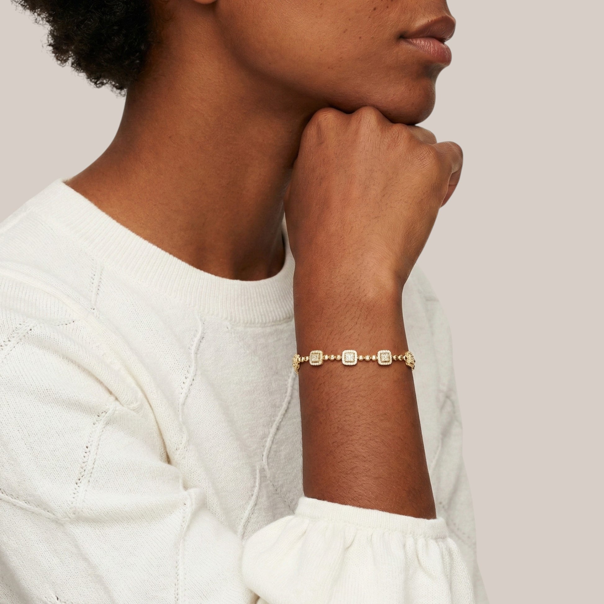 Person wearing a gold bracelet on a plain background