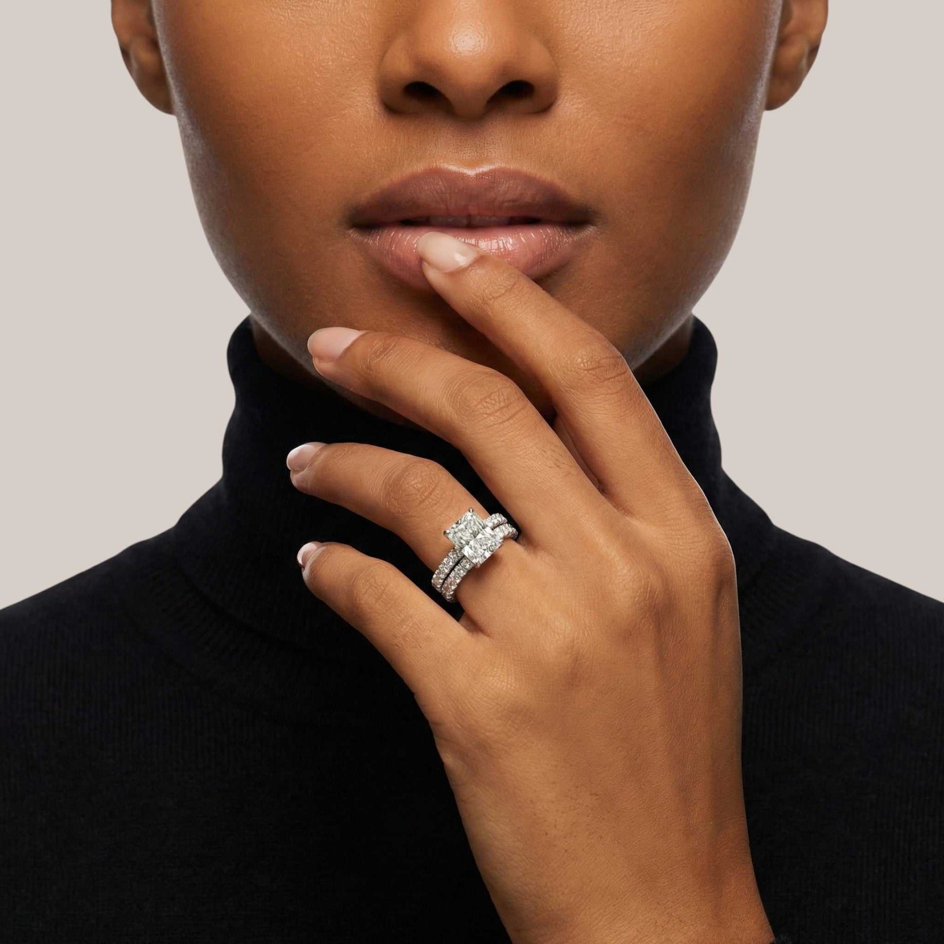 Close-up of a woman's hand wearing a diamond ring with a neutral background