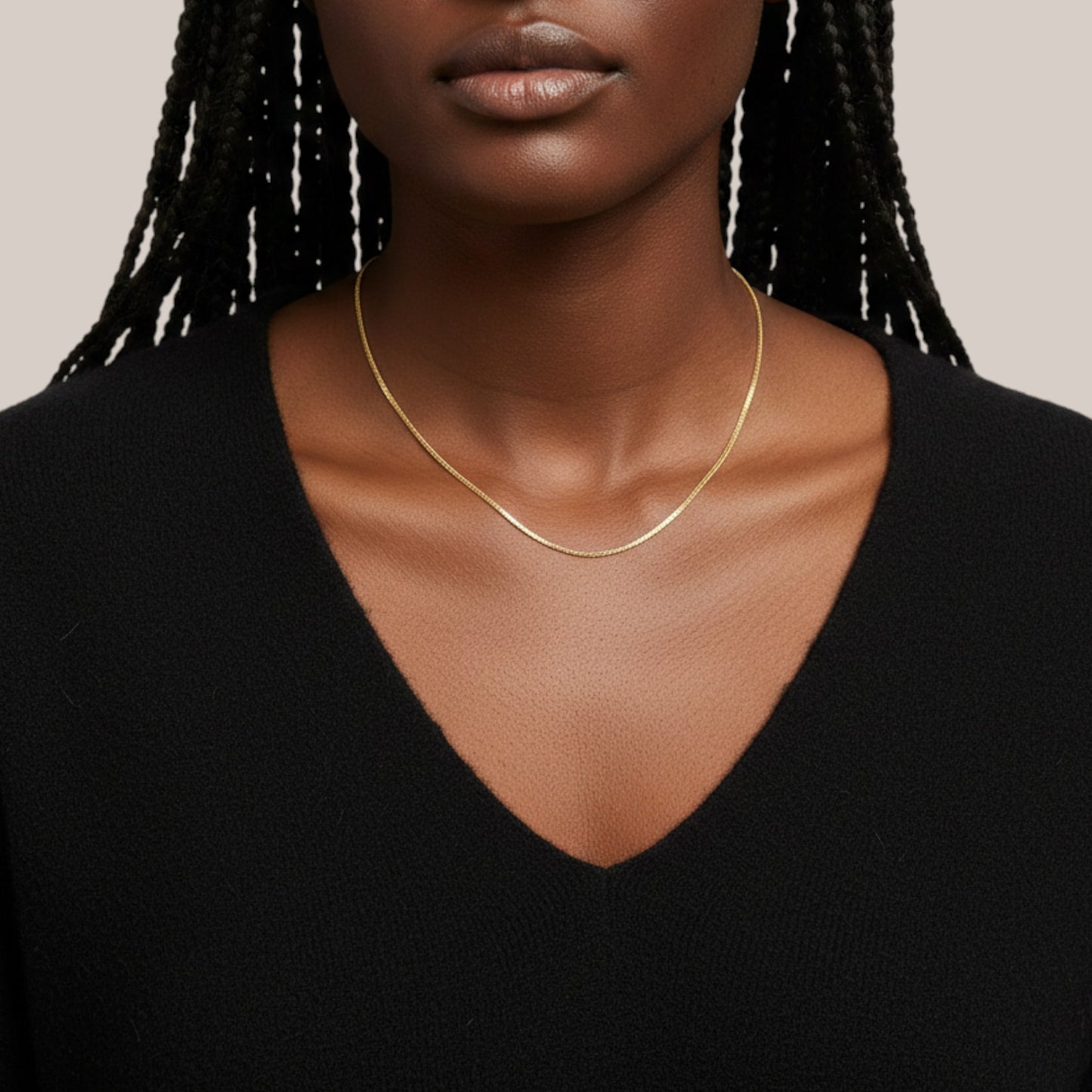 Woman wearing a gold necklace against a neutral background