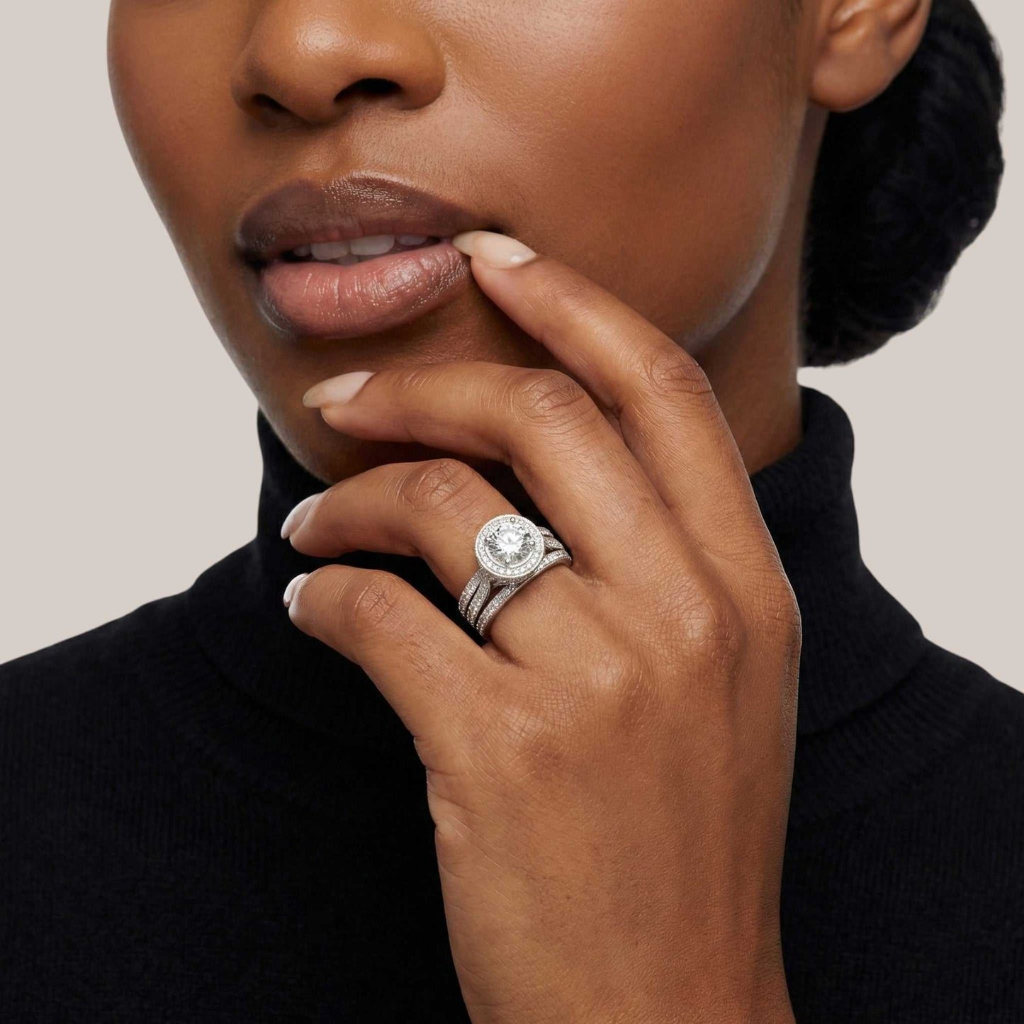 Woman wearing a diamond ring on her finger with a neutral background