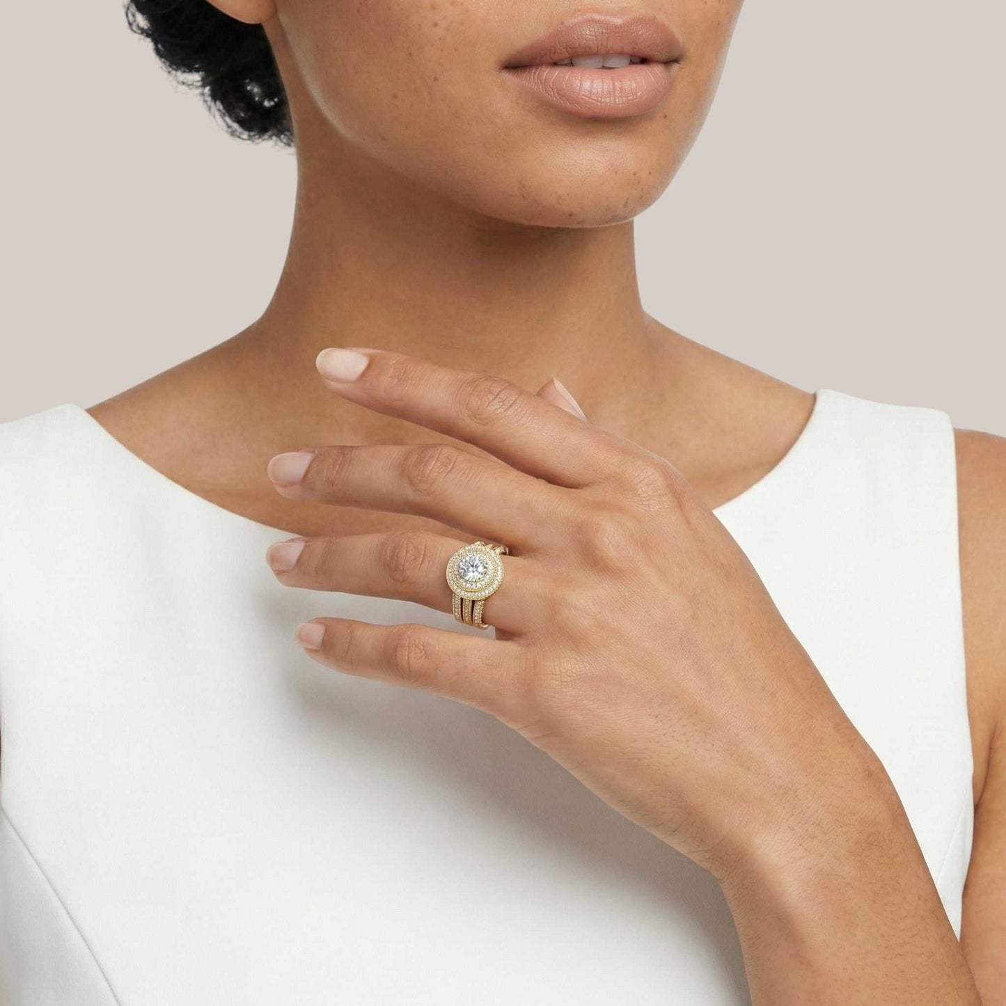 Close-up of a person wearing a gold ring with a diamond on a plain background