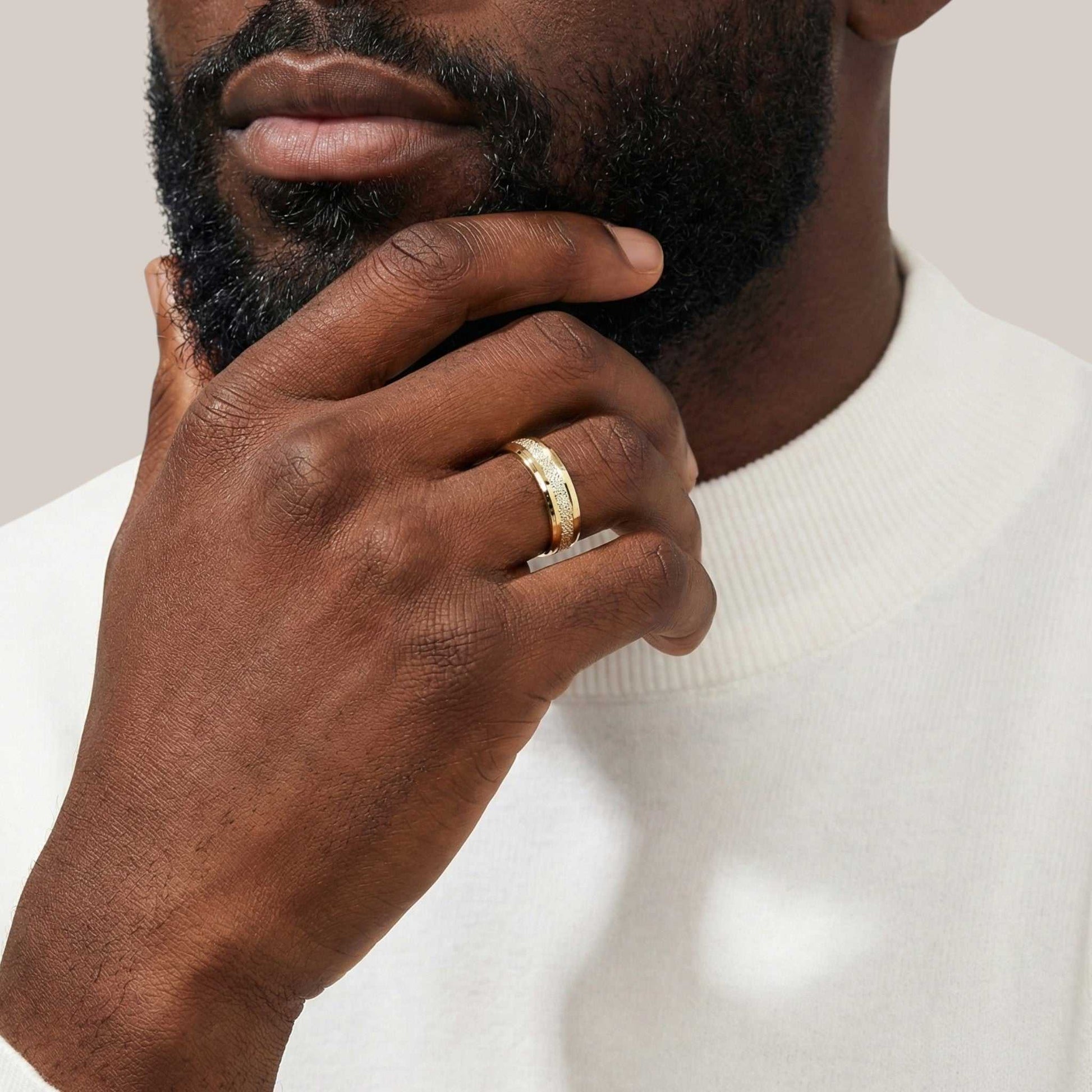 Man wearing a gold ring on his finger with a neutral background