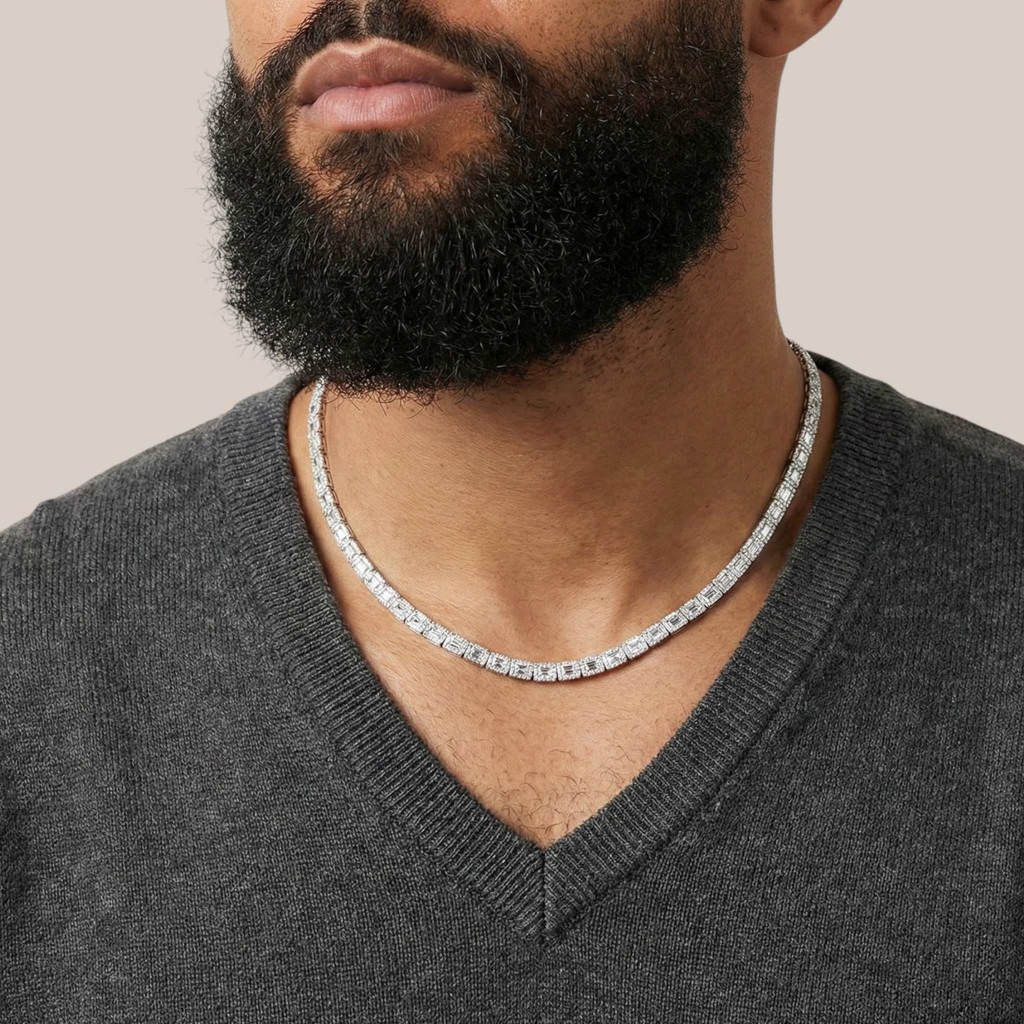 Man wearing a silver chain necklace with a neutral background