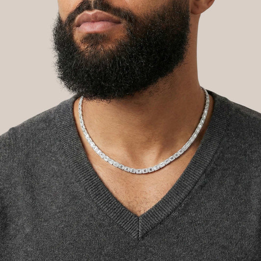 Man wearing a silver chain necklace with a neutral background