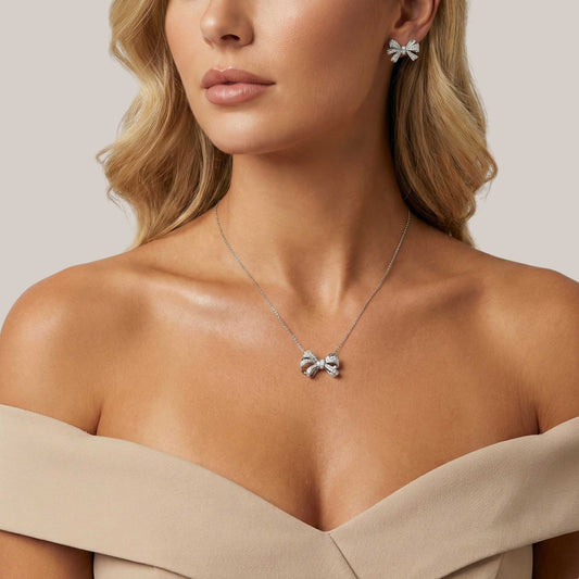 Woman wearing a silver necklace with a butterfly pendant against a neutral background
