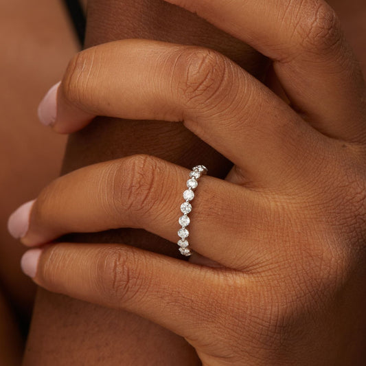 Close-up of a hand wearing a diamond ring on a brown background