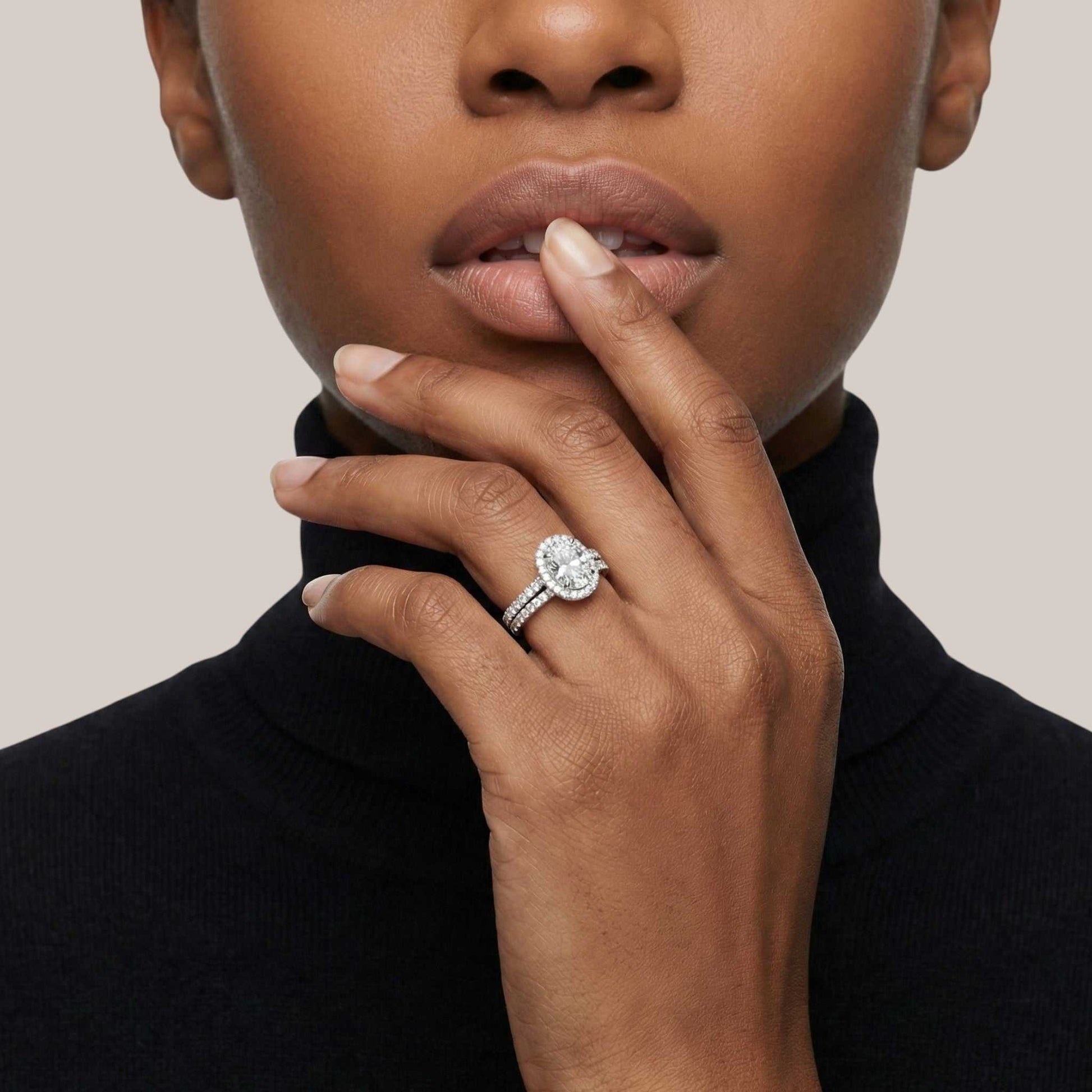 Close-up of a woman's hand wearing a diamond ring on a neutral background