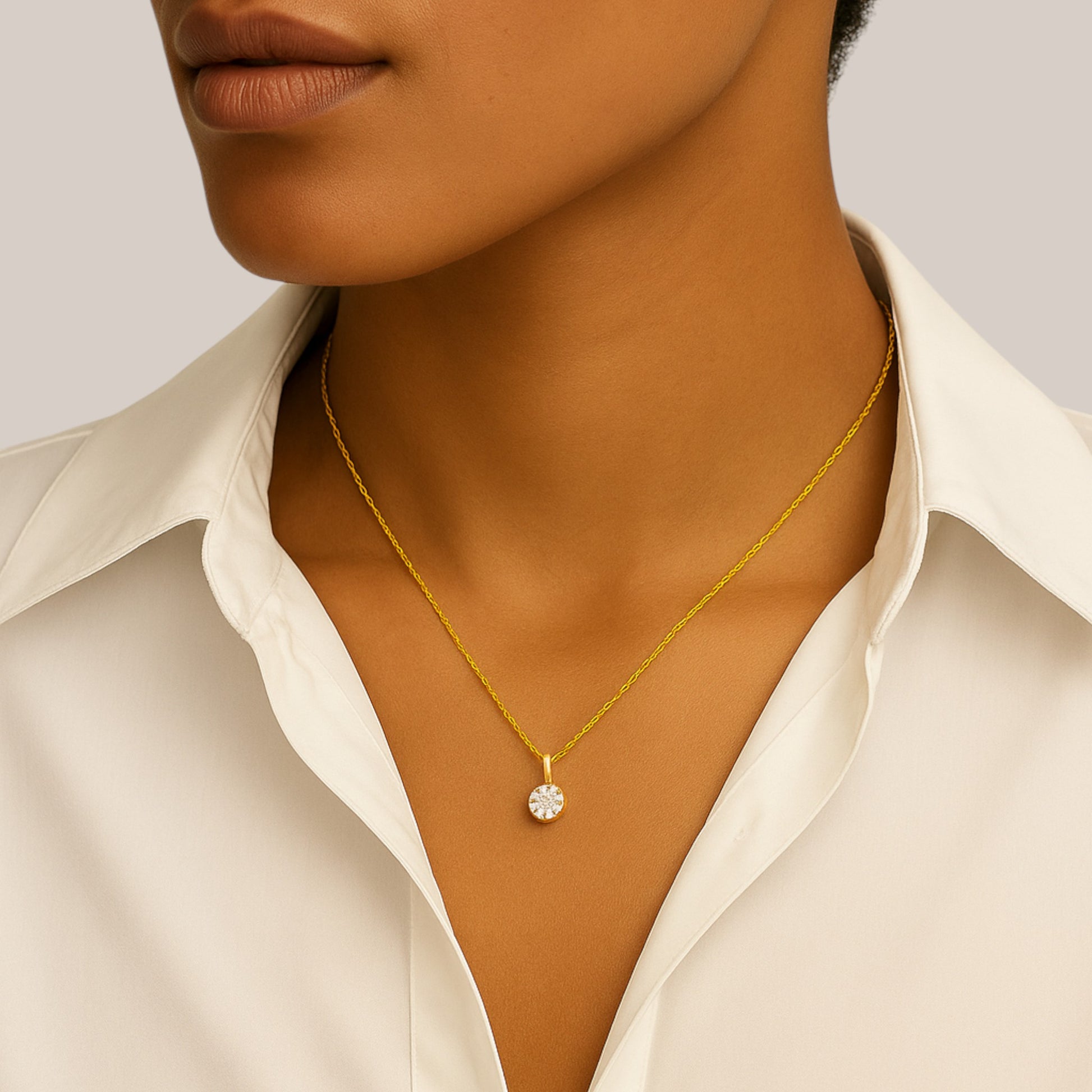 Gold necklace with a pendant worn by a person in a white shirt.