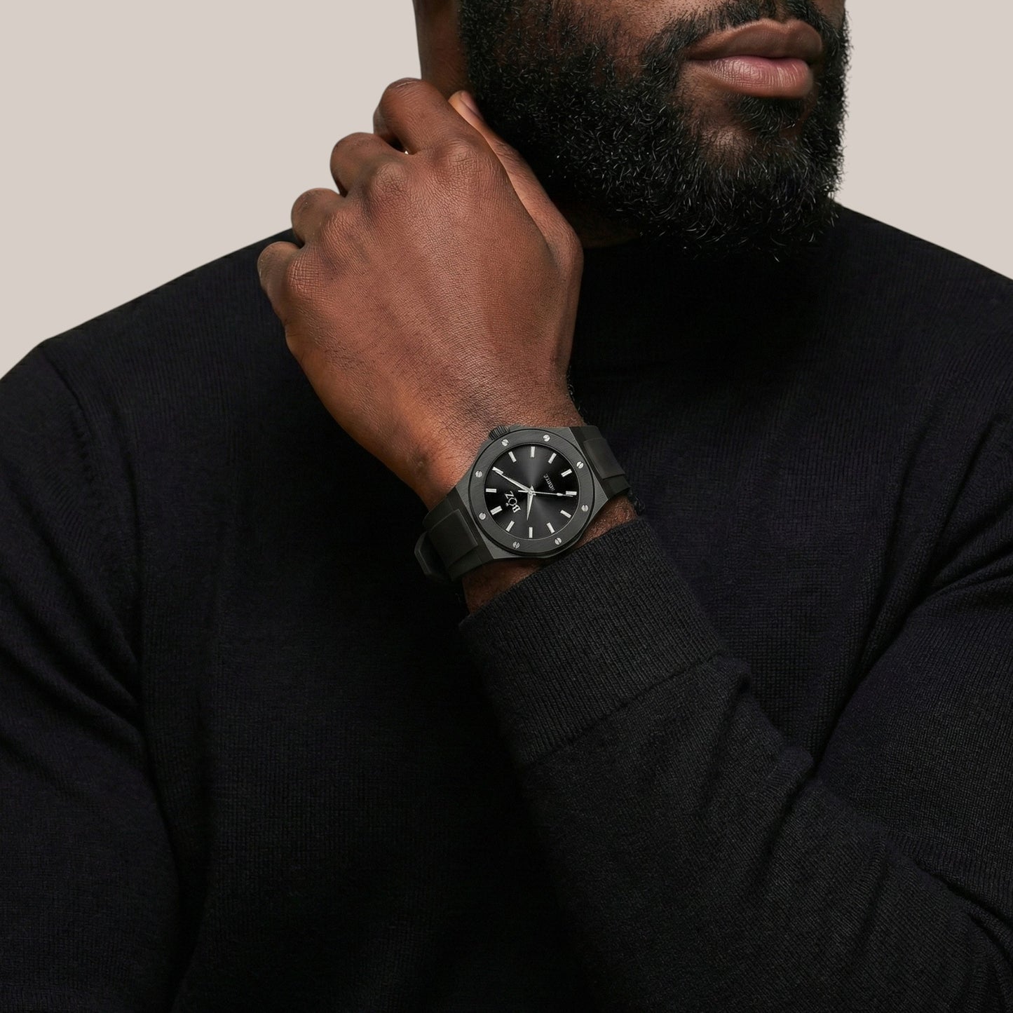 Man wearing a black watch on his wrist with a neutral background