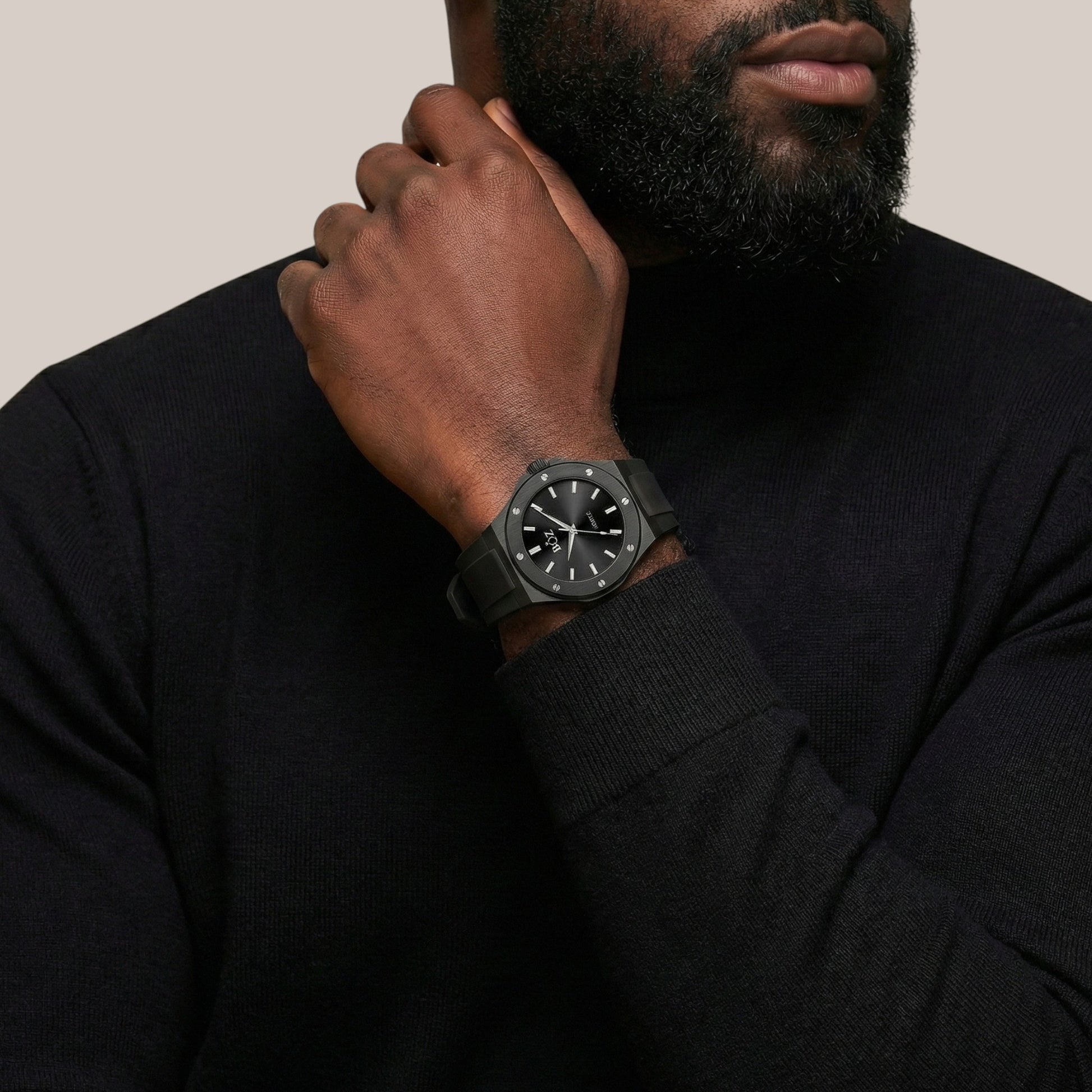 Man wearing a black watch on his wrist with a neutral background