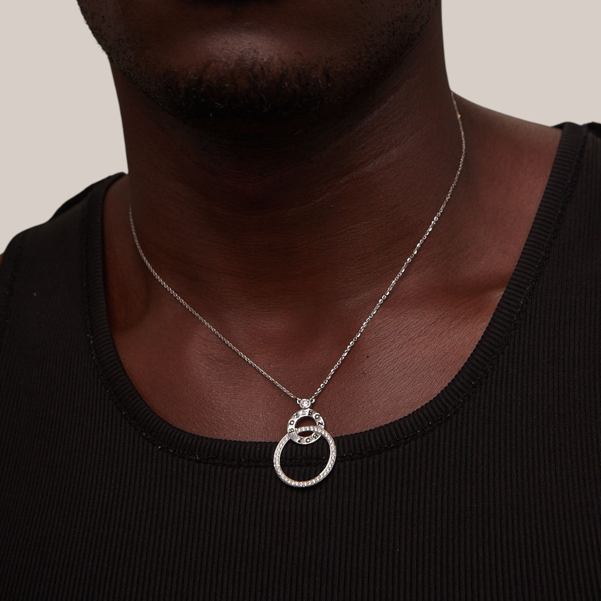 Silver necklace with a double ring pendant on a person wearing a black shirt.