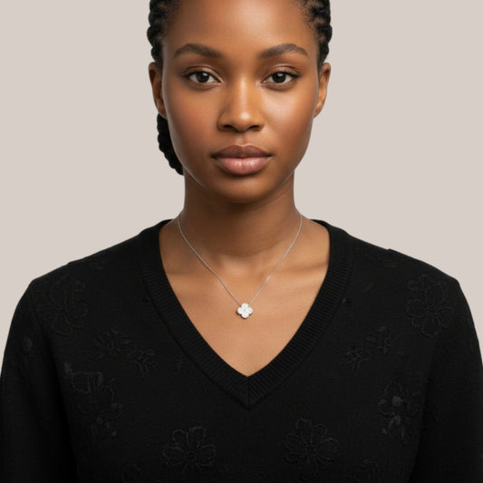 Woman wearing a black sweater with floral patterns and a silver necklace on a beige background
