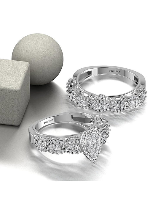 Two 18K gold rings with pear cut diamonds, one larger and one smaller, displayed on a reflective surface with a grey sphere in the background.