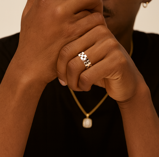 Close-up of a hand wearing a gold ring with a necklace featuring a pearl pendant.