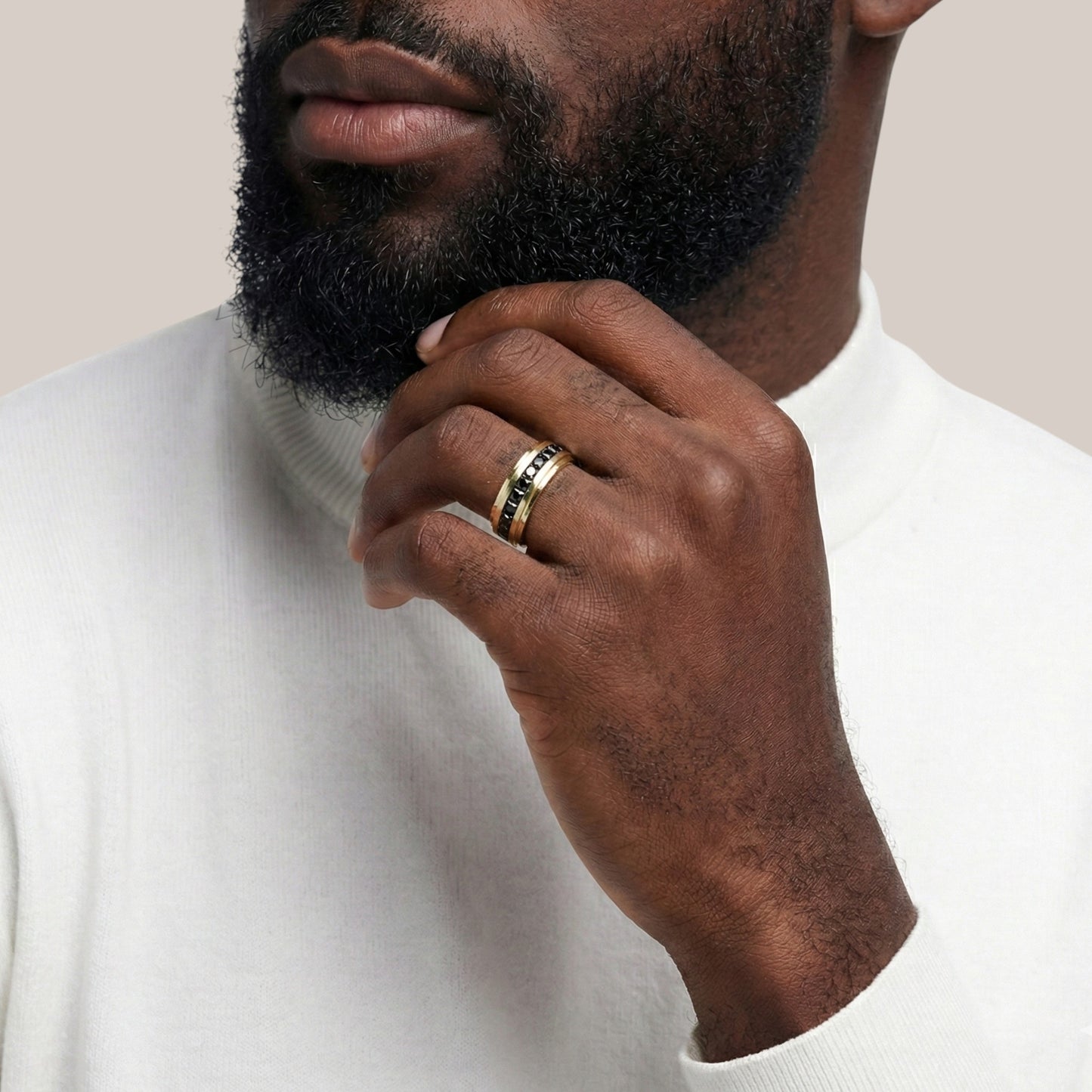 Man wearing a gold ring on his finger, with a neutral background