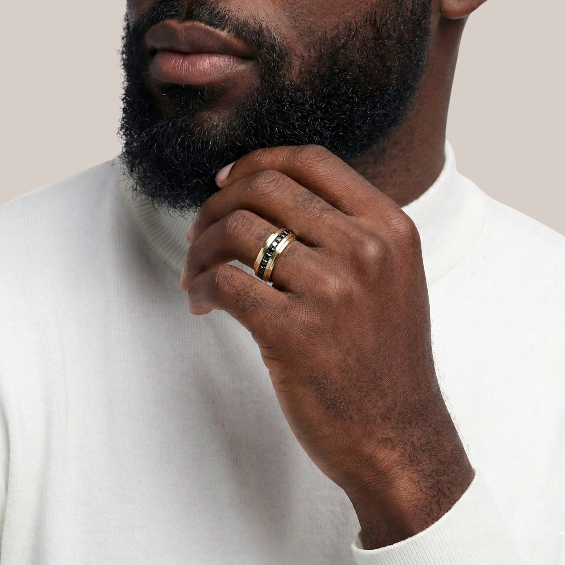 Man wearing a gold ring on his finger, with a neutral background