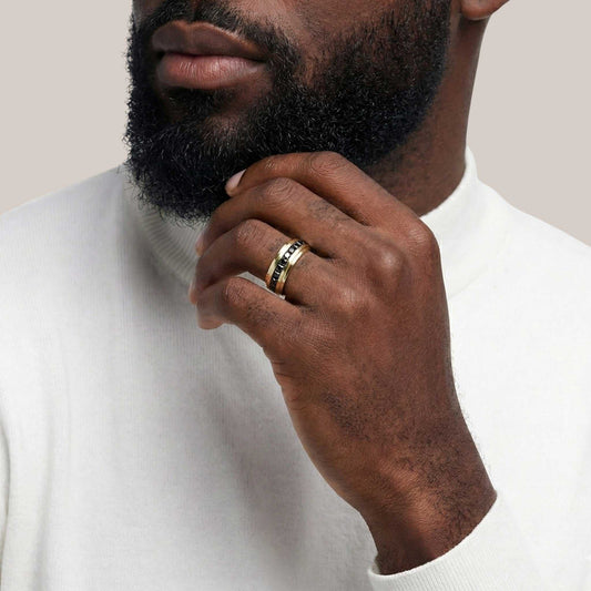 Man wearing a gold ring on his finger, with a neutral background