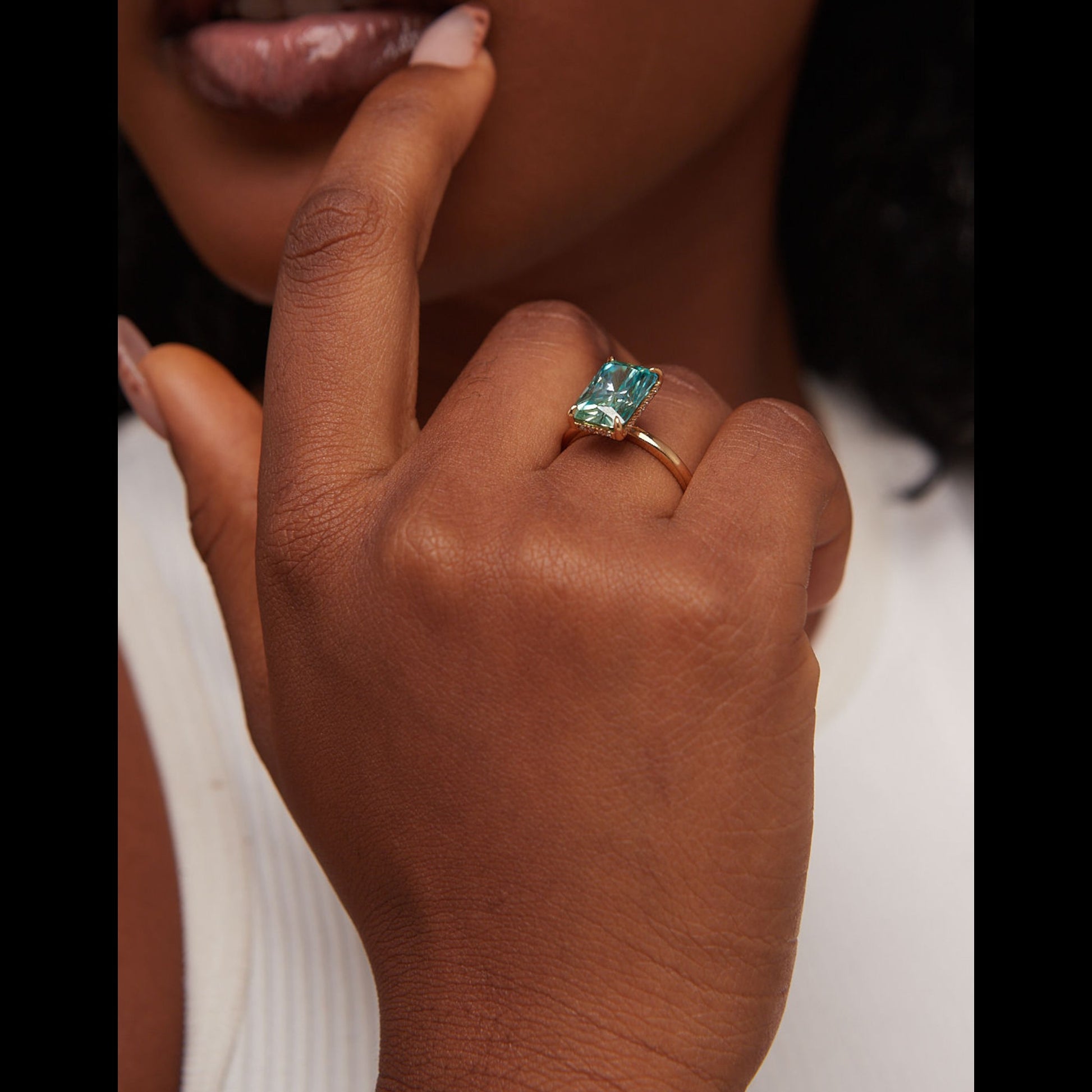 Close-up of a hand wearing a ring with a green gemstone.