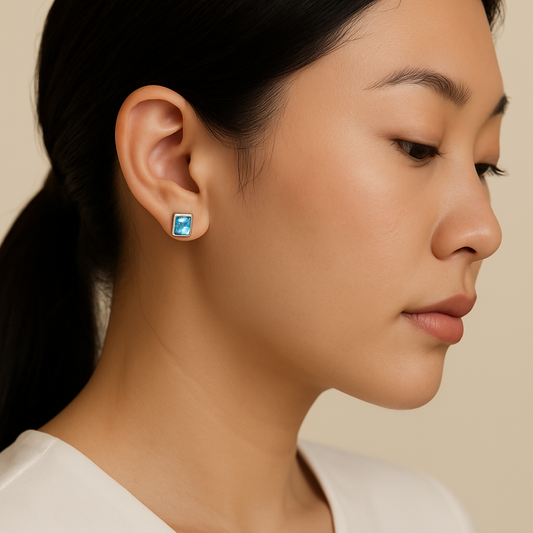 Close-up of a woman wearing a blue earring against a beige background