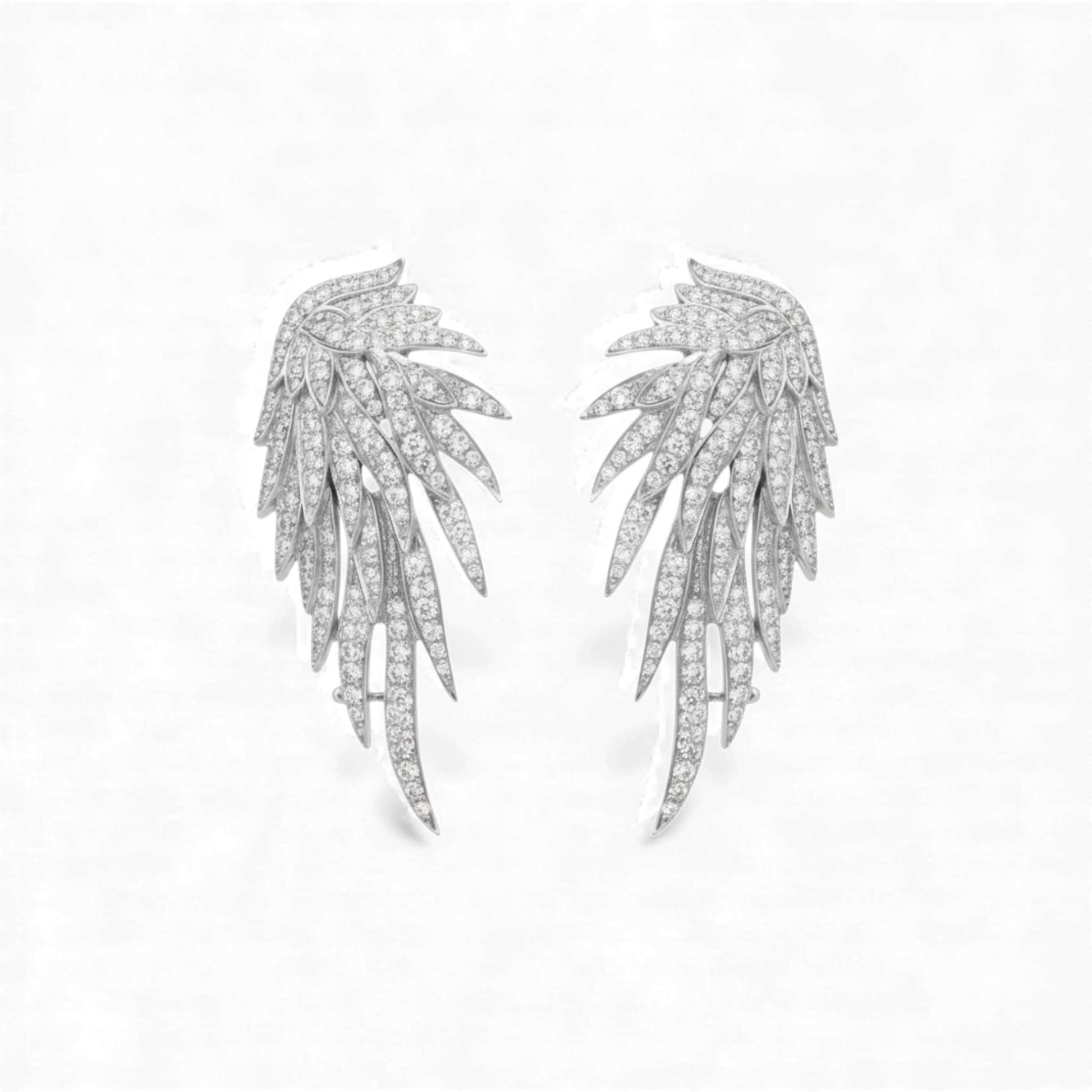 Pair of silver leaf-shaped earrings on a light gray background