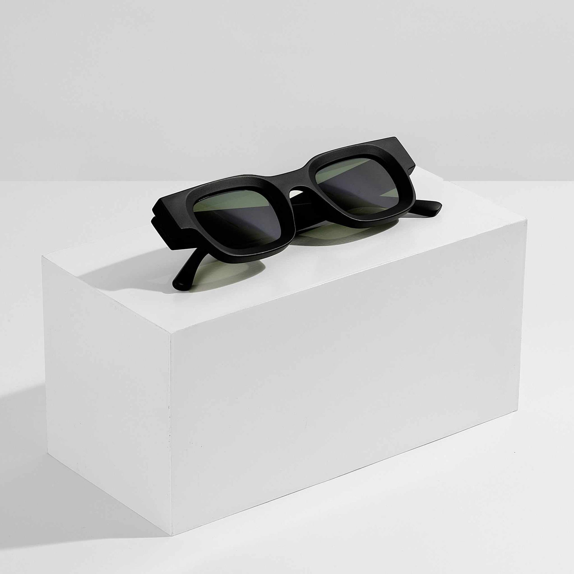 Black sunglasses on a white cube with a white background