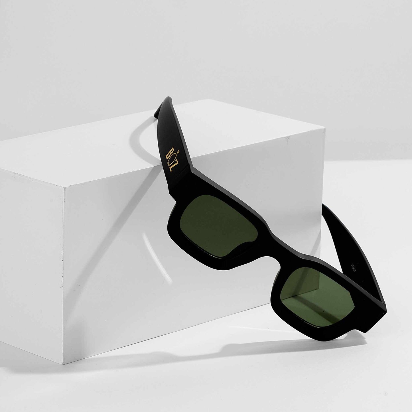 Black sunglasses with green lenses on a white background