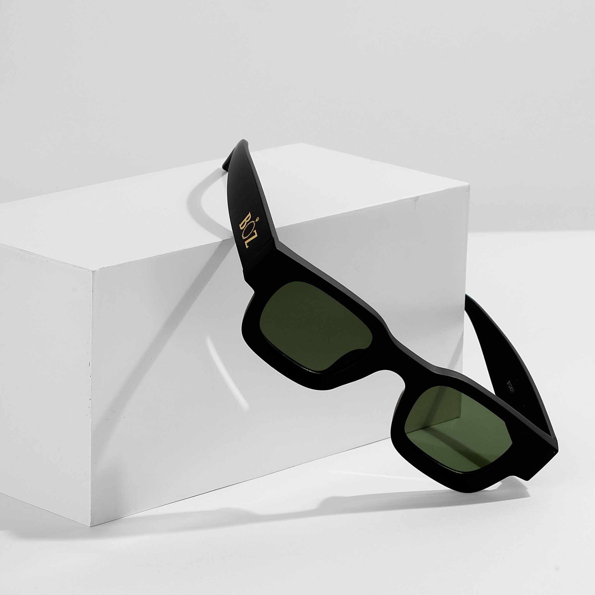 Black sunglasses with green lenses on a white background
