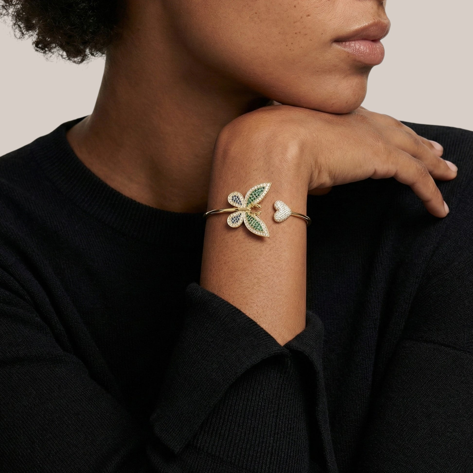 Person wearing a bracelet with leaf design on a neutral background