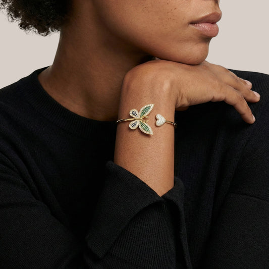 Person wearing a bracelet with leaf design on a neutral background