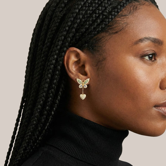 Close-up of a woman wearing butterfly-shaped earrings with a neutral background