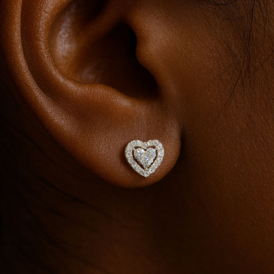 Heart-shaped earring on an ear with a dark background