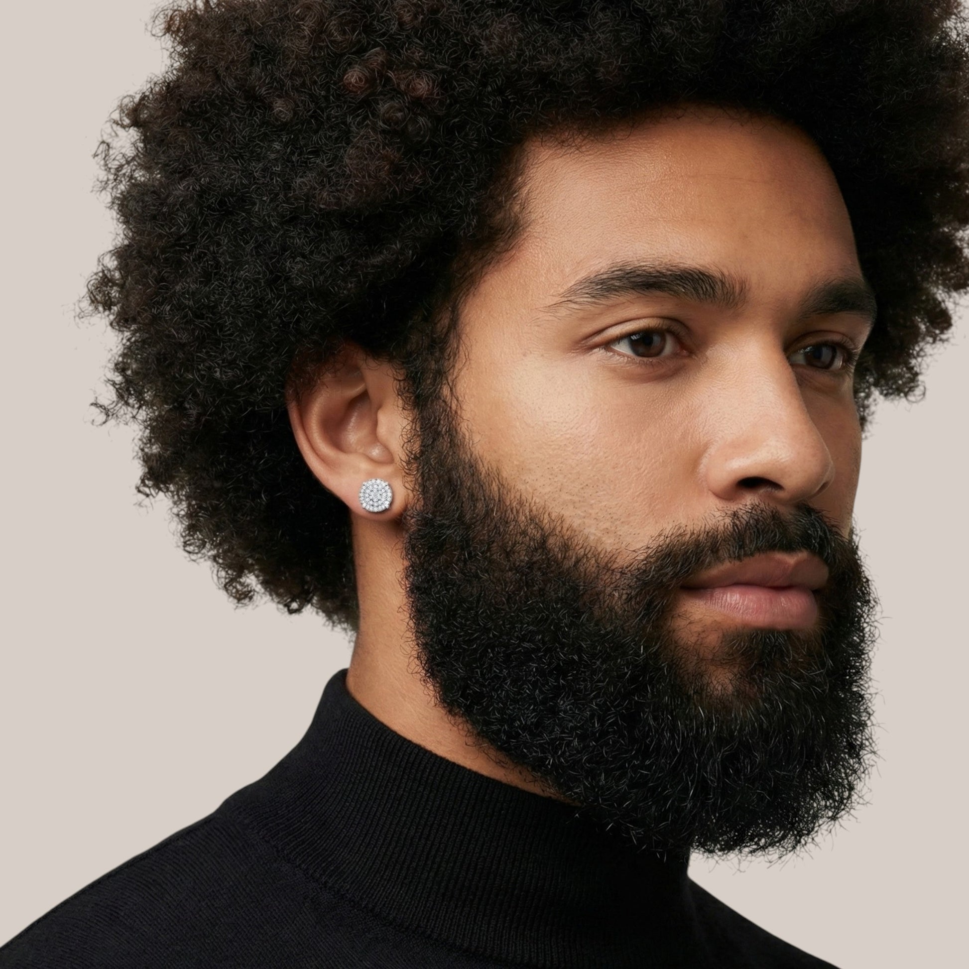Man with a beard wearing a black turtleneck against a neutral background