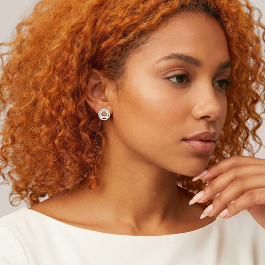 Woman with curly hair wearing a white top against a neutral background