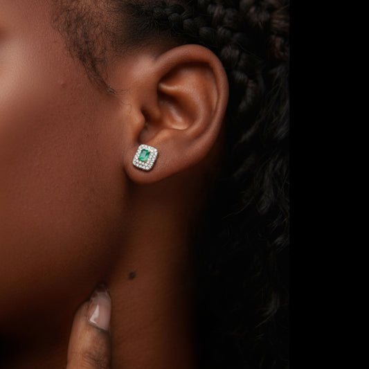 Close-up of an ear wearing a diamond and emerald earring.