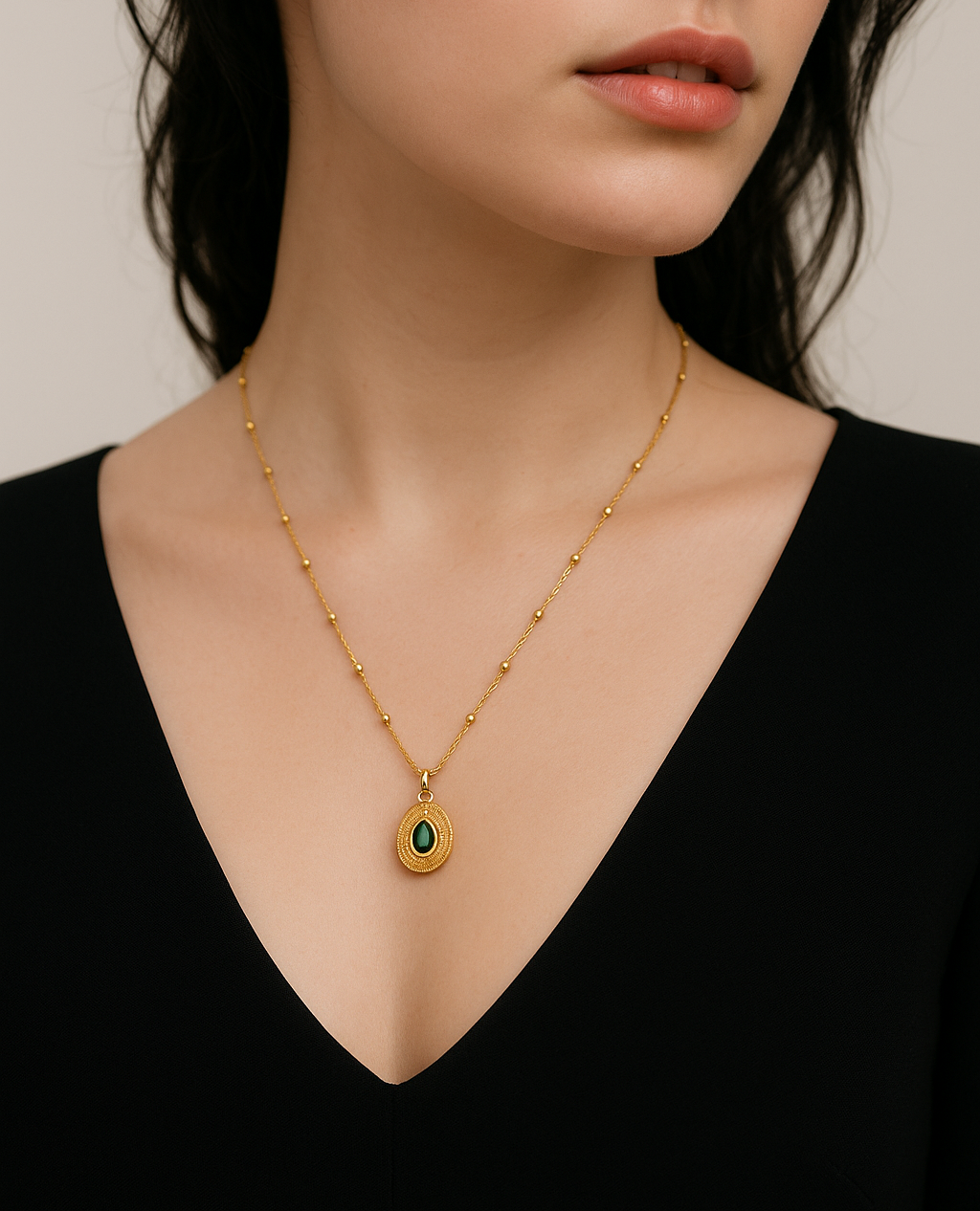 Woman wearing a gold necklace with a pendant against a neutral background