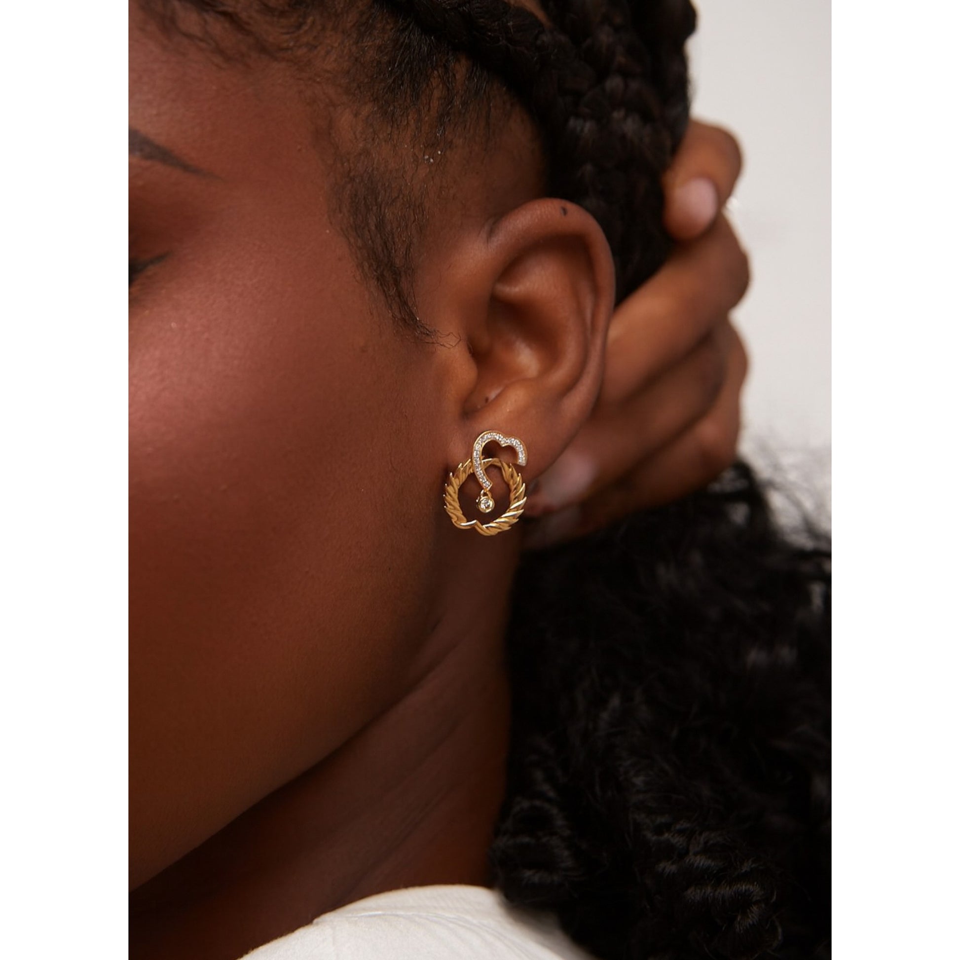 Close-up of a person wearing a gold earring with a decorative design.