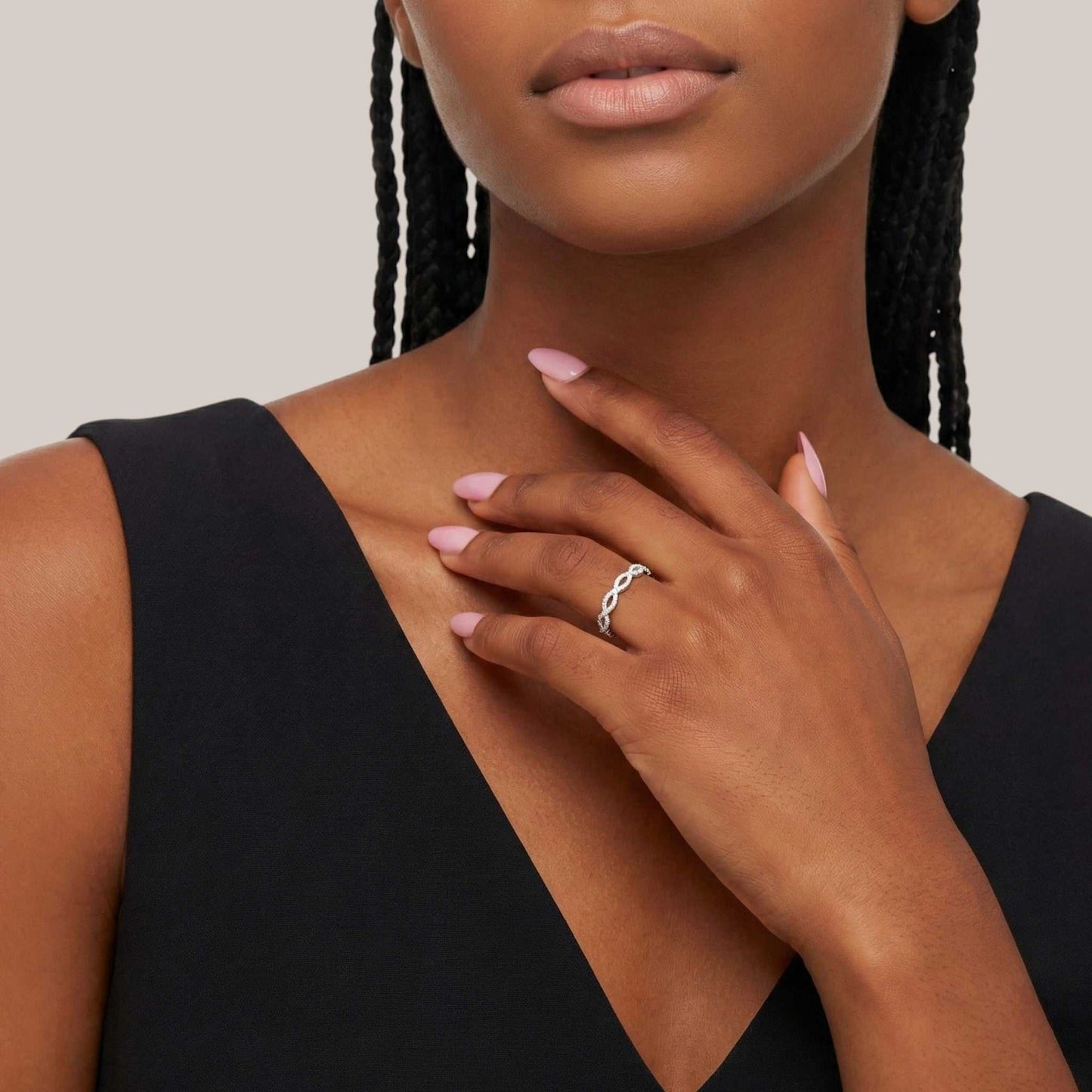 Woman wearing a black dress with a ring on her finger, against a neutral background