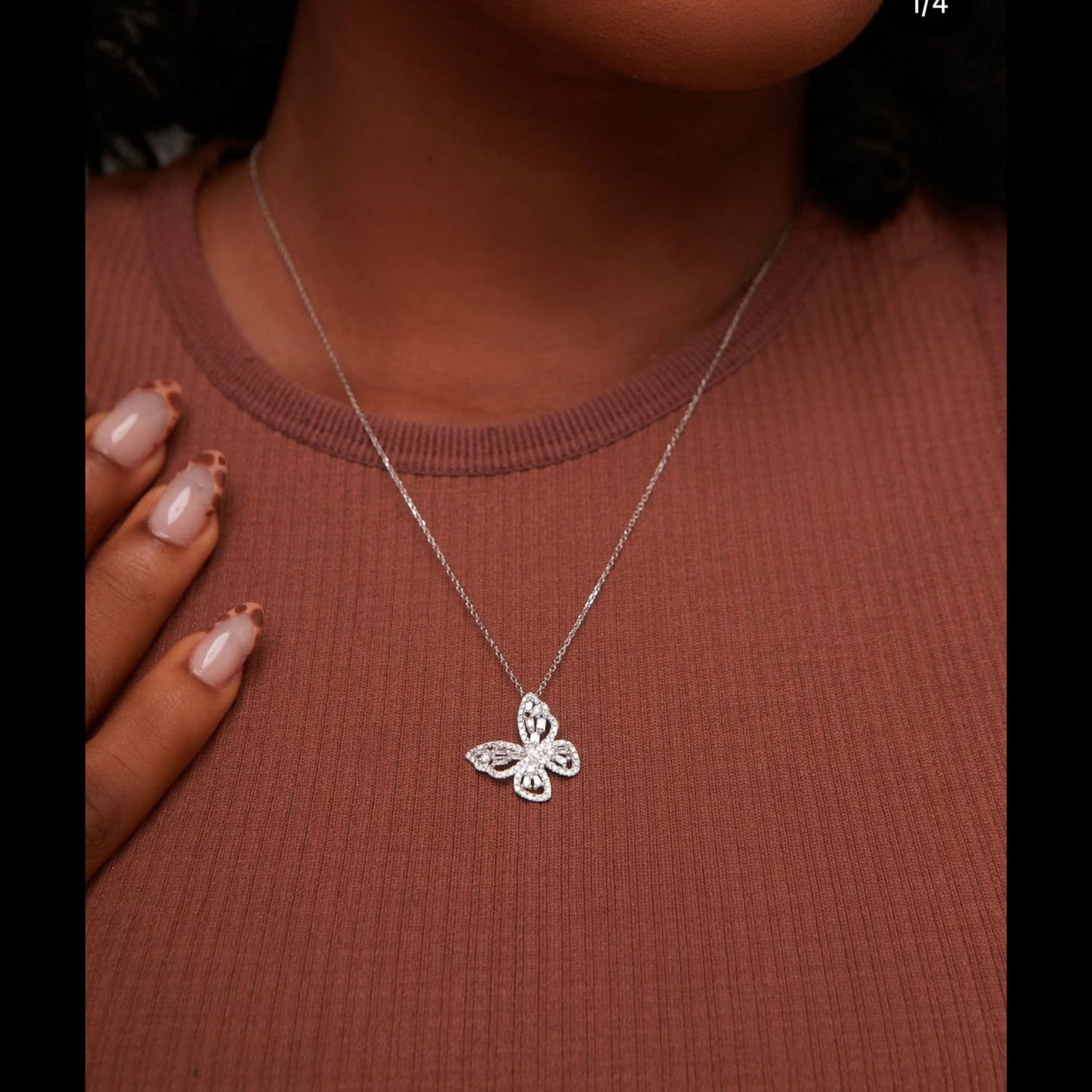 Silver butterfly necklace on a person wearing a brown top