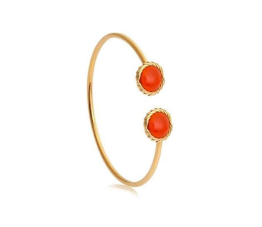 Gold bangle with two red stones on a white background