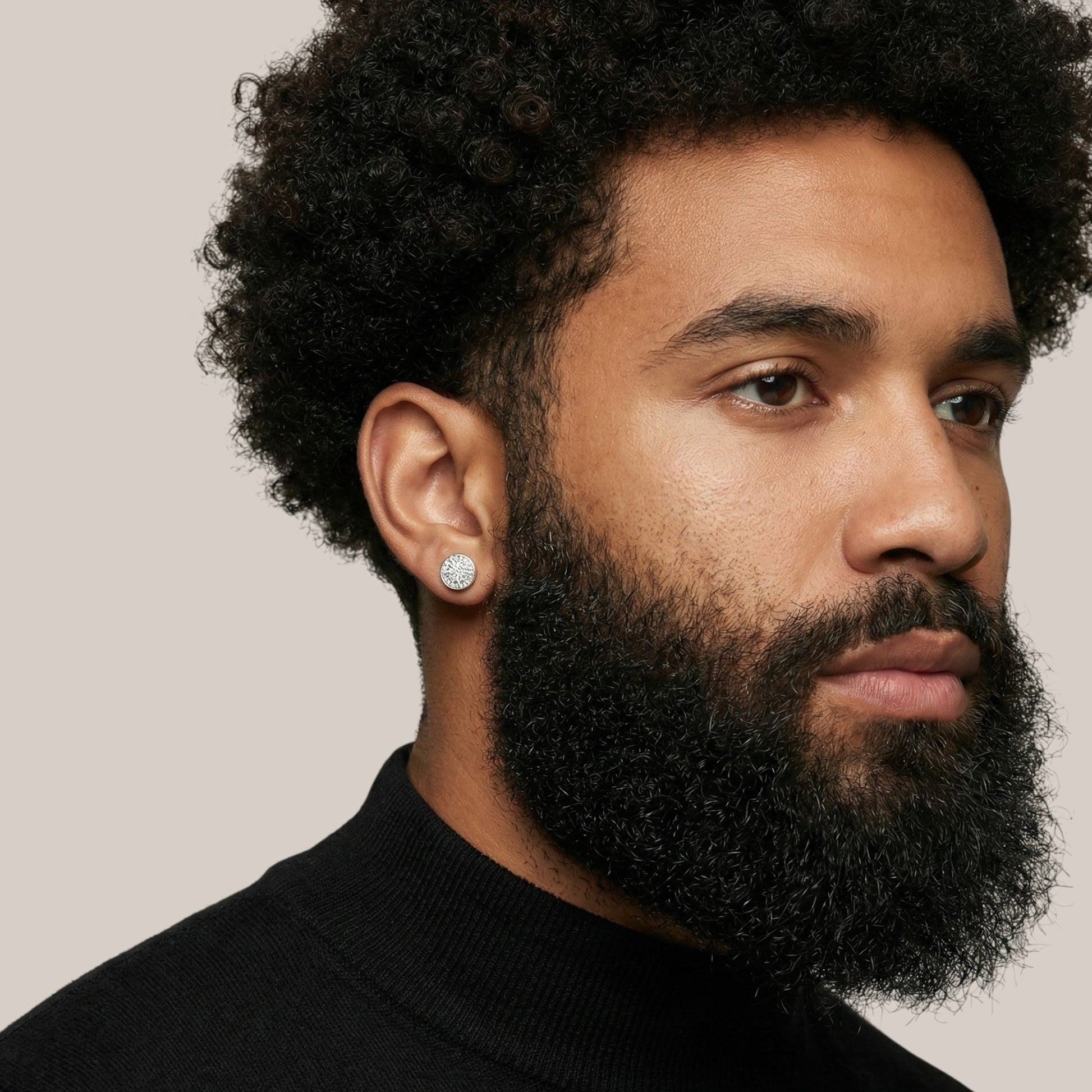 Man with a beard wearing a black turtleneck against a neutral background