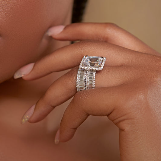 Close-up of a hand wearing a diamond ring with a beige background