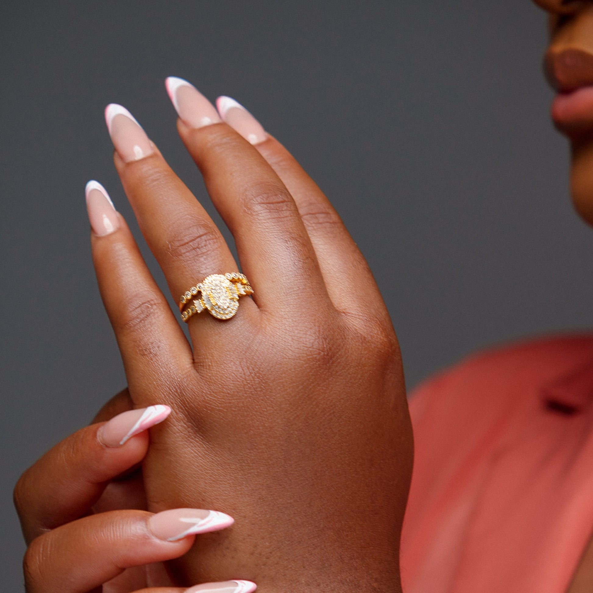 Hand wearing a gold ring with a dark gray background