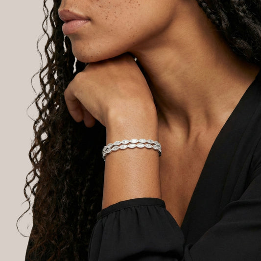 Woman wearing a silver bracelet on her wrist with a neutral background