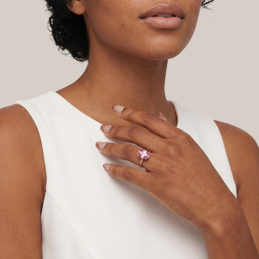 Woman wearing a pink ring on her hand against a neutral background