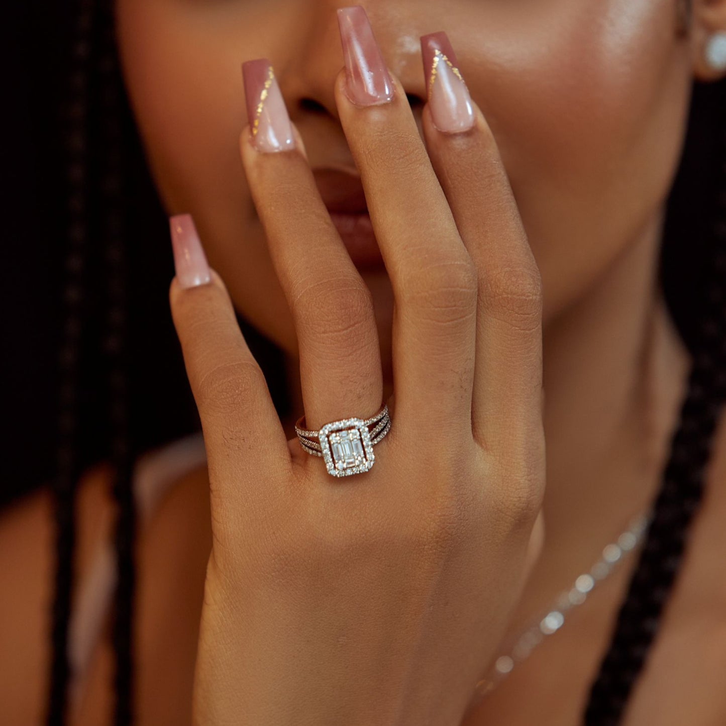 Close-up of a hand wearing a diamond ring with a blurred background