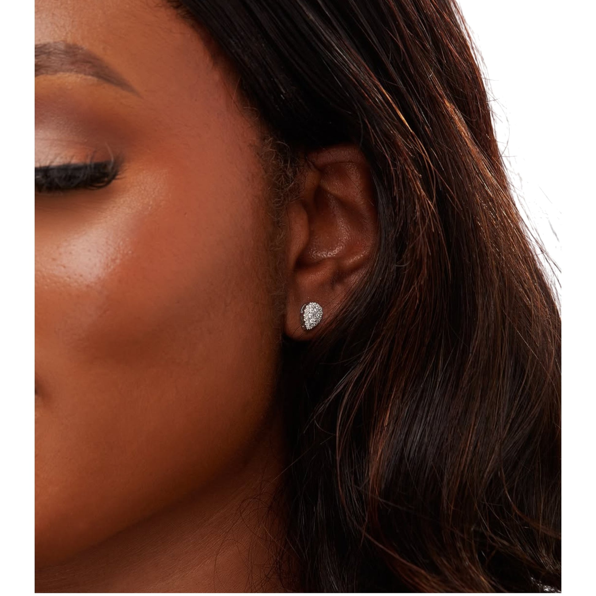 Close-up of a woman wearing a diamond earring on a white background