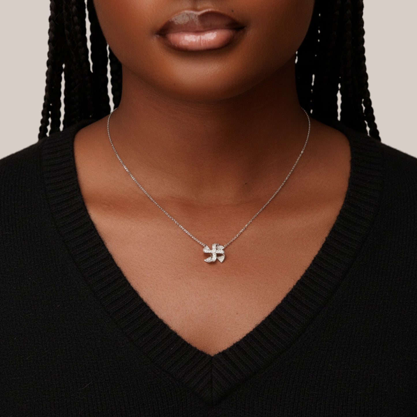 Person wearing a silver necklace with a unique pendant against a neutral background